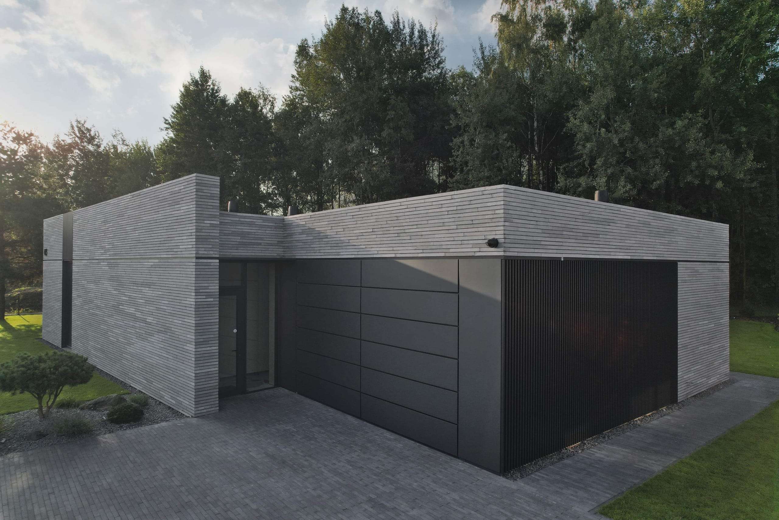 Modern Family House — in daylight, low volumes meeting a dark garage door