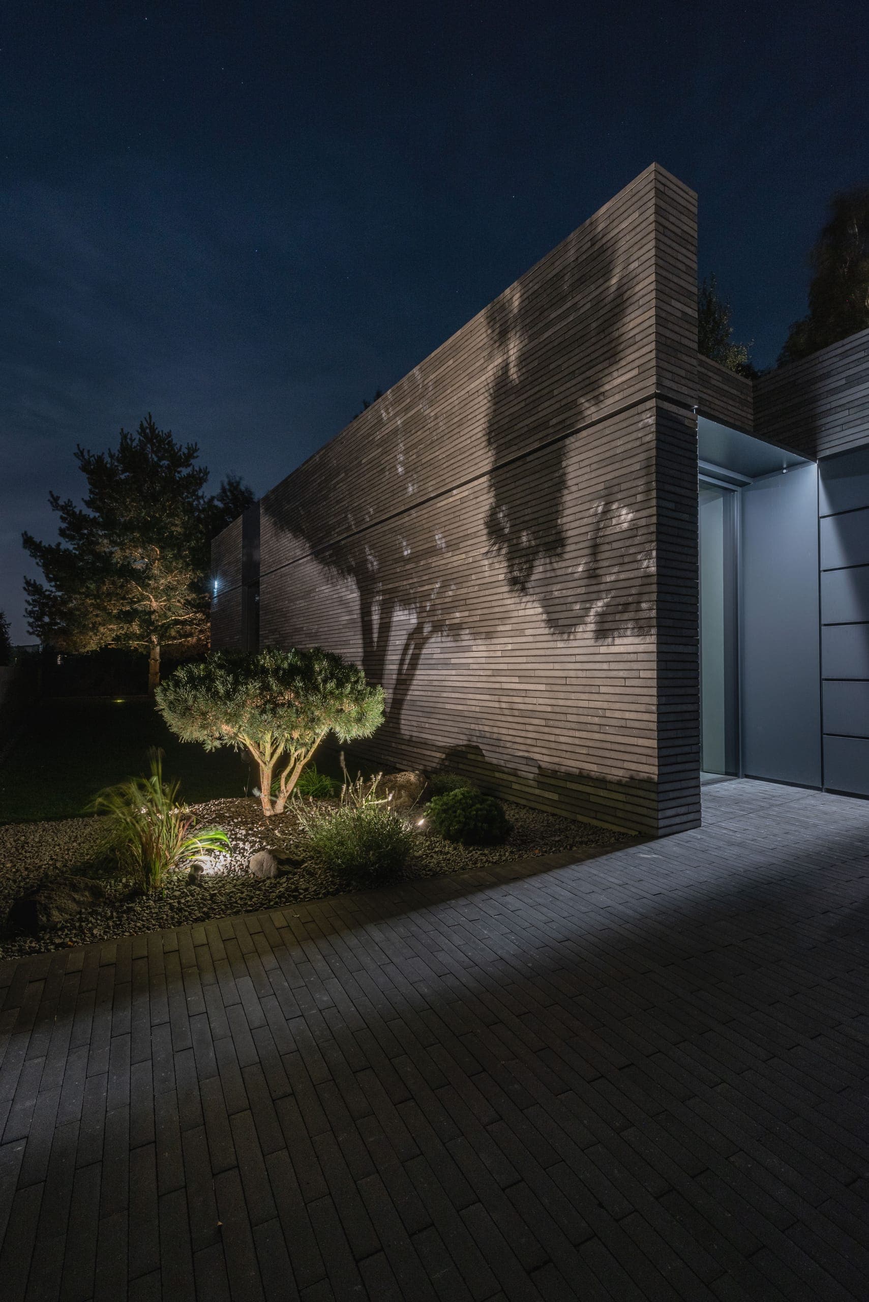 Modern Family House — tree shadows cast across the brick wall by garden uplighting