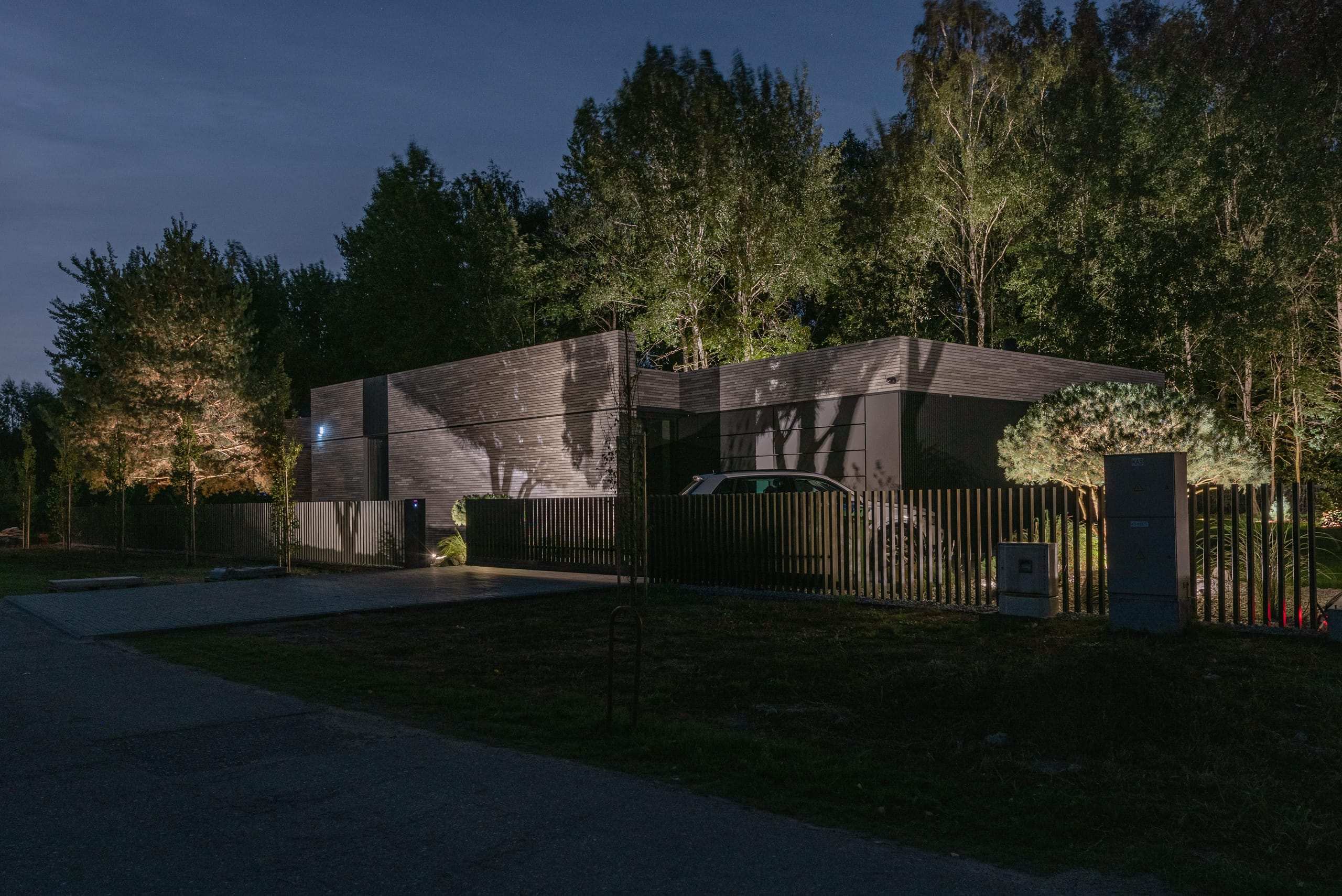 Modern Family House — at night from the road, brick walls washed with light