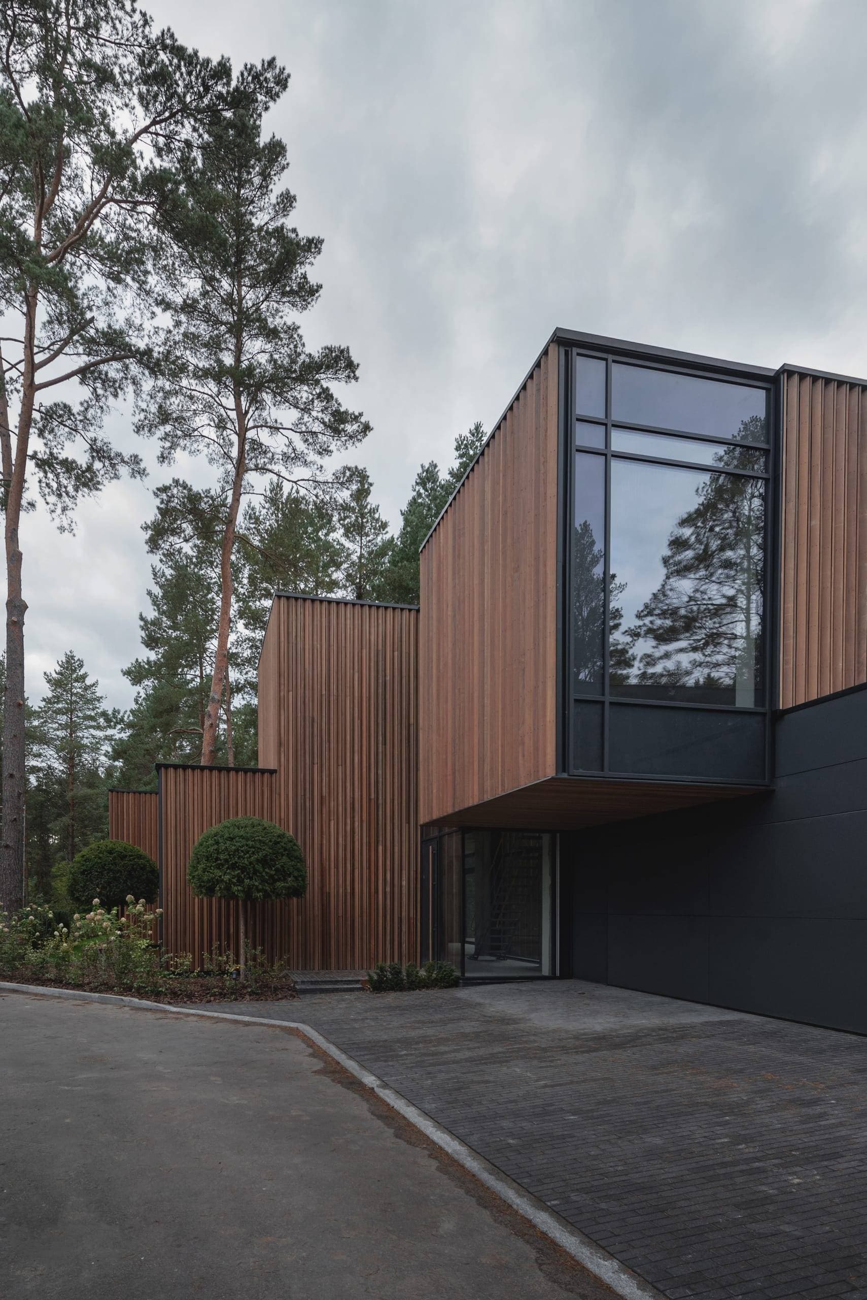 ZEN House — vertical timber cladding and a double-height glazed corner under an overcast sky