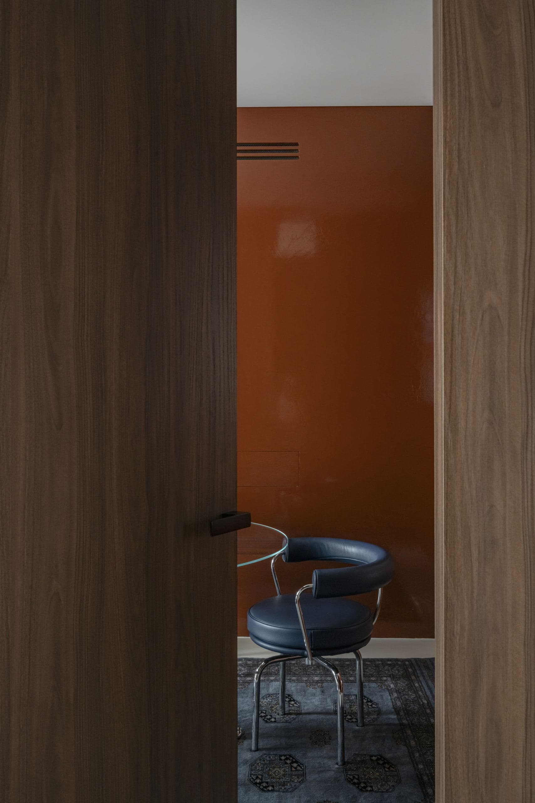 Bespoke Office Interior — orange lacquered door opening onto a chair beyond