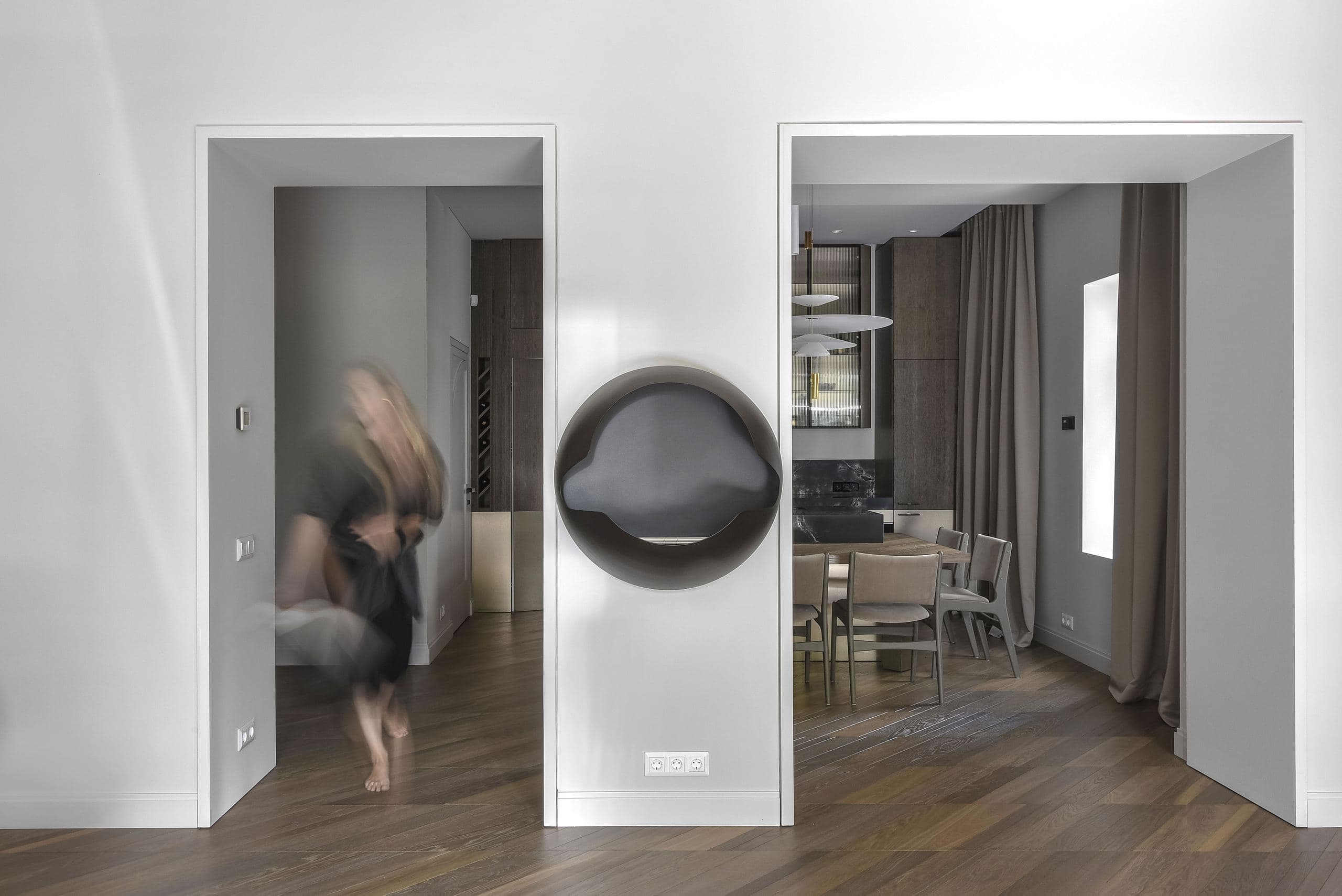 City Avenue Apartment — figure walking past a round mirrored doorway between rooms