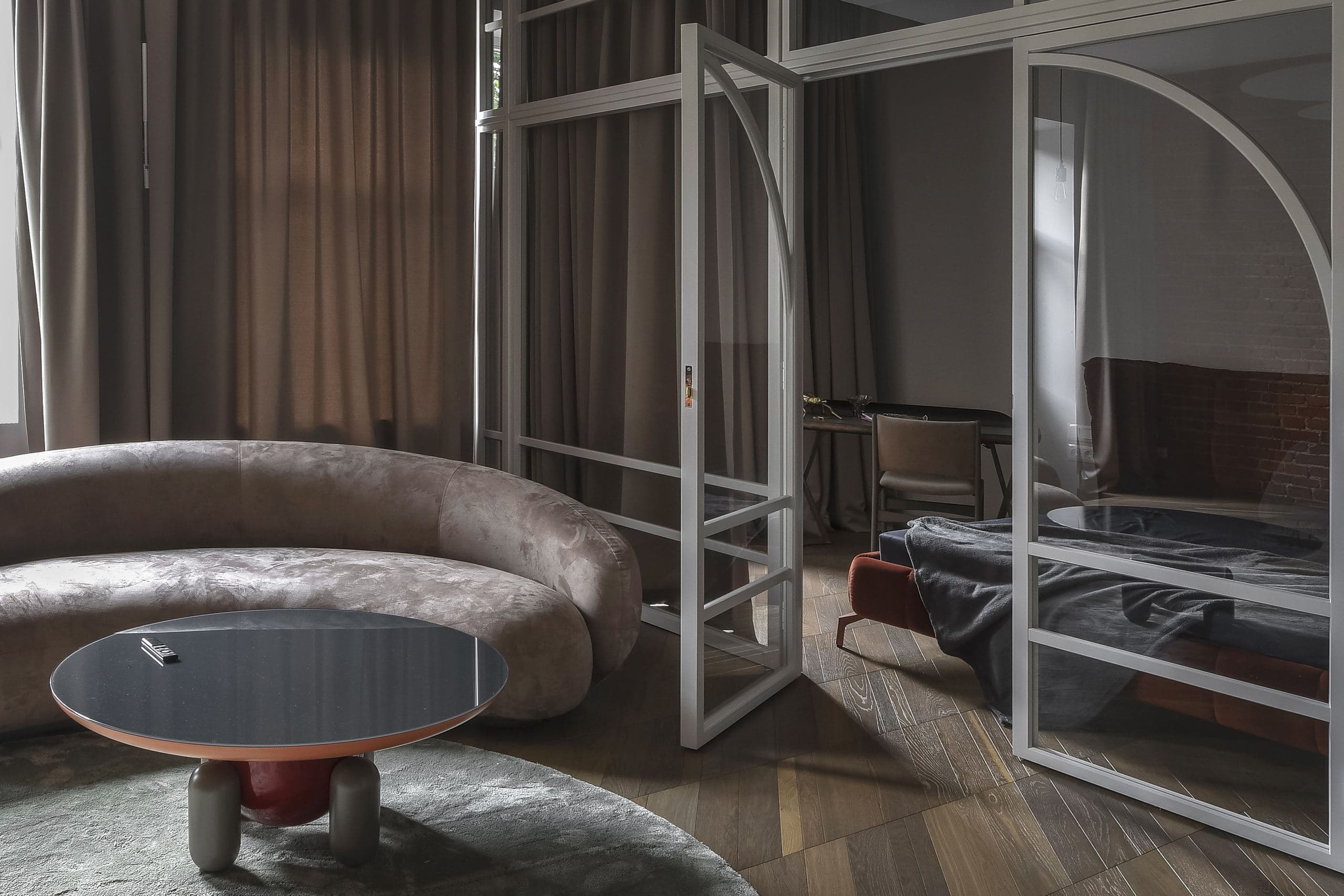 City Avenue Apartment — curved velvet sofa beside a glass-panelled partition