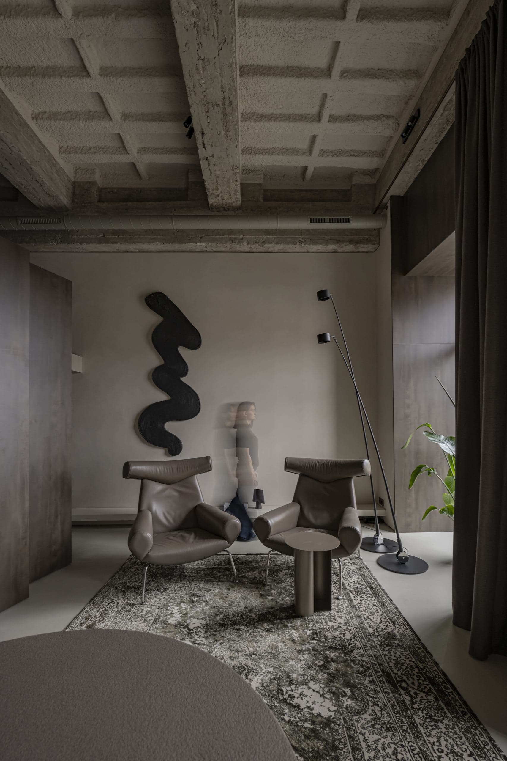 Loft Office — sculptural black wall piece beneath the exposed concrete-beam ceiling