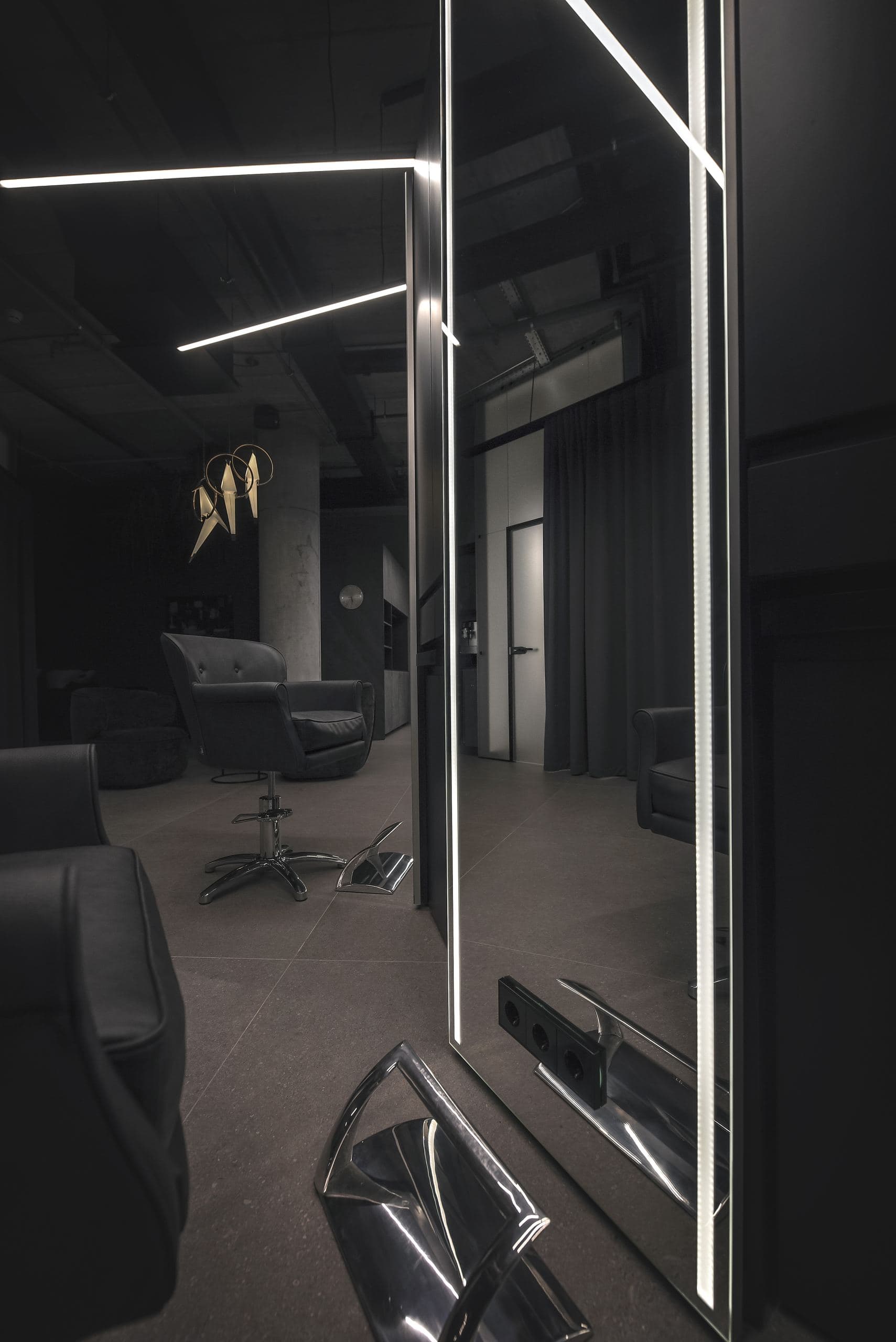 Maestro Beauty Salon — angled ceiling light strips above a curtain, a gold pendant sculpture beyond