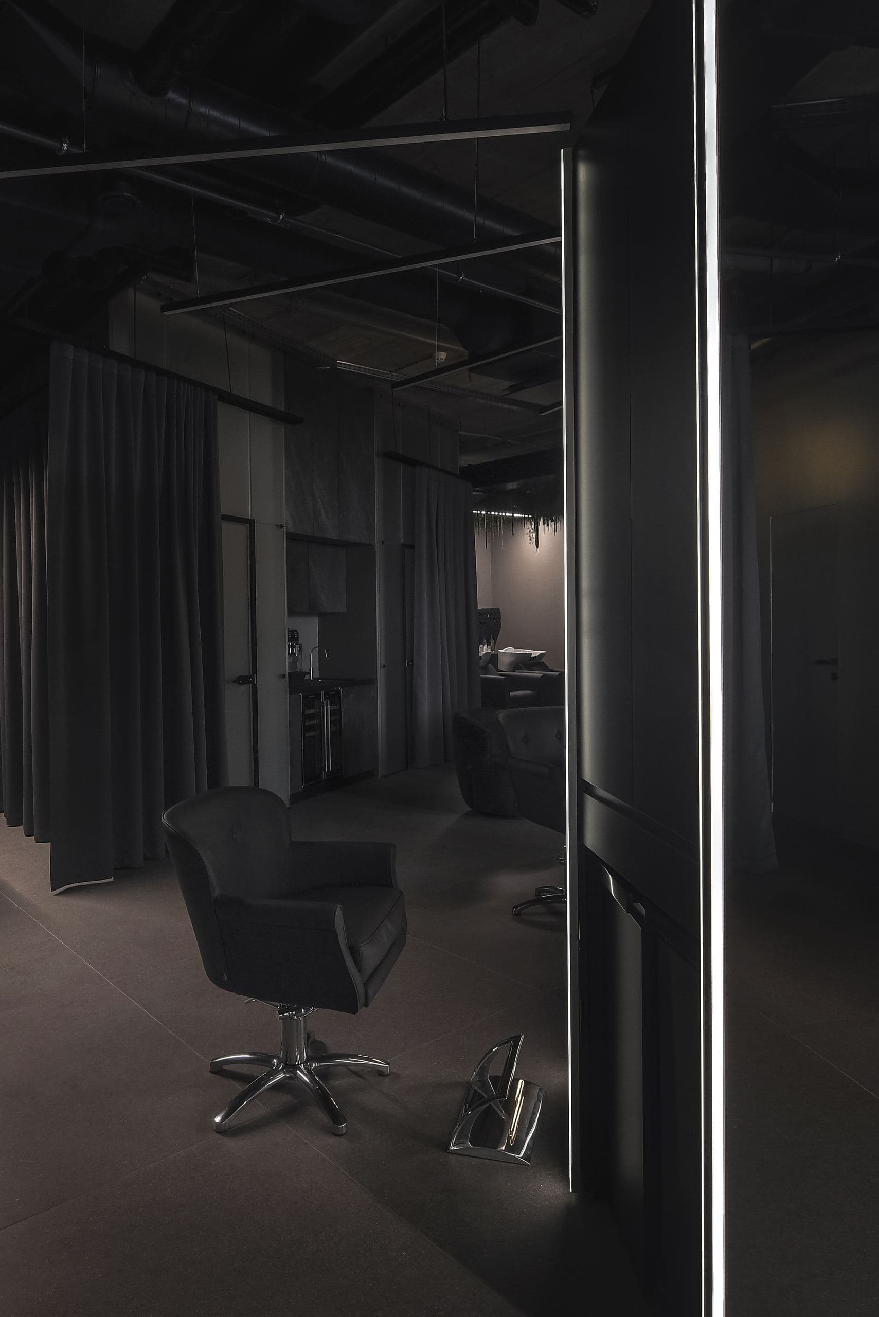 Maestro Beauty Salon — curtained corridor beneath exposed ceiling pipes and a linear light