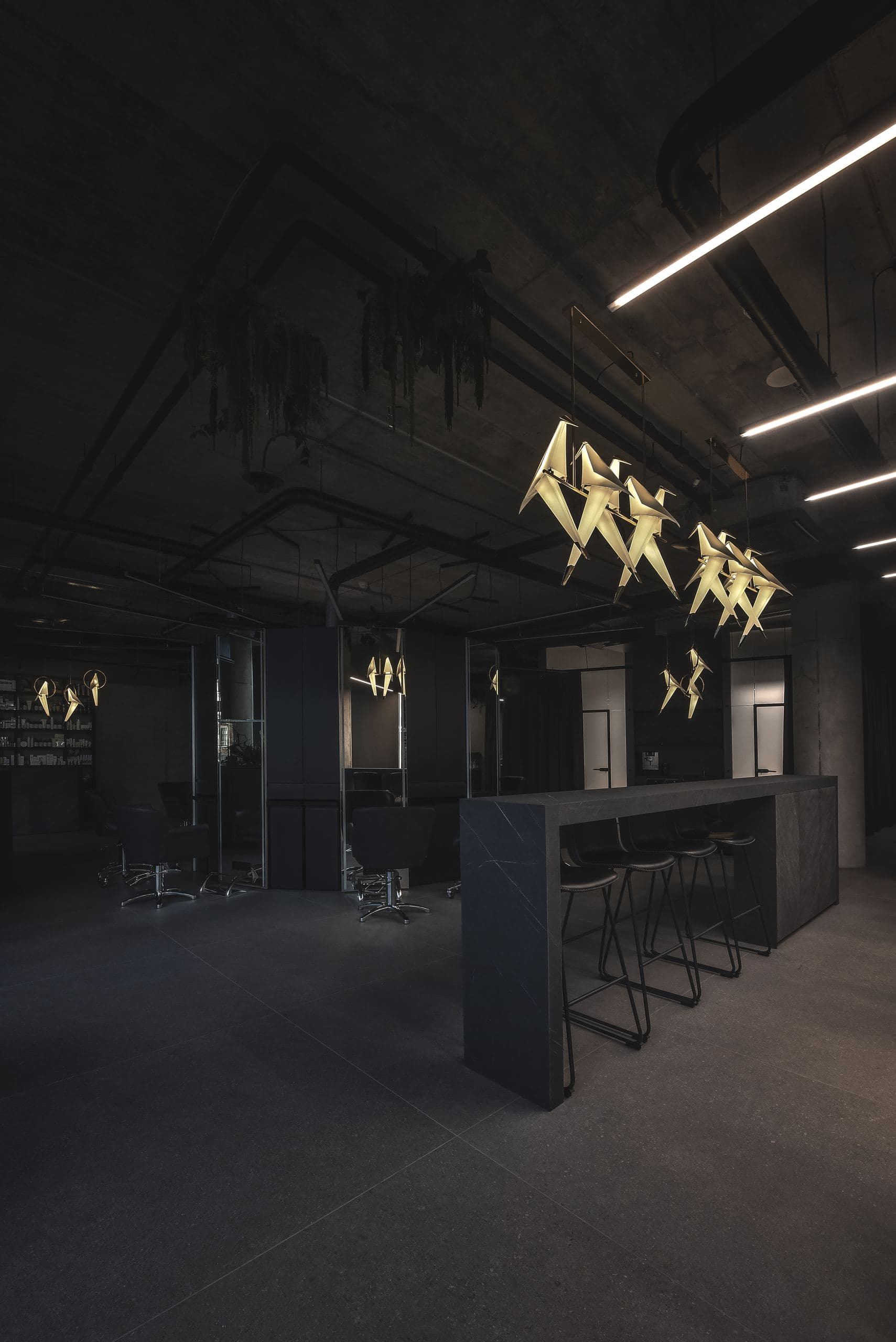 Maestro Beauty Salon — gold origami-fish pendants above the reception island and bar stools