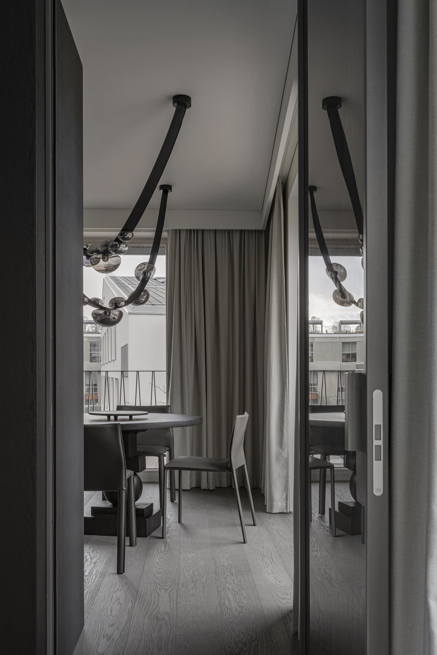 Paupys Apartment — folding glass door reflecting the dining table beyond