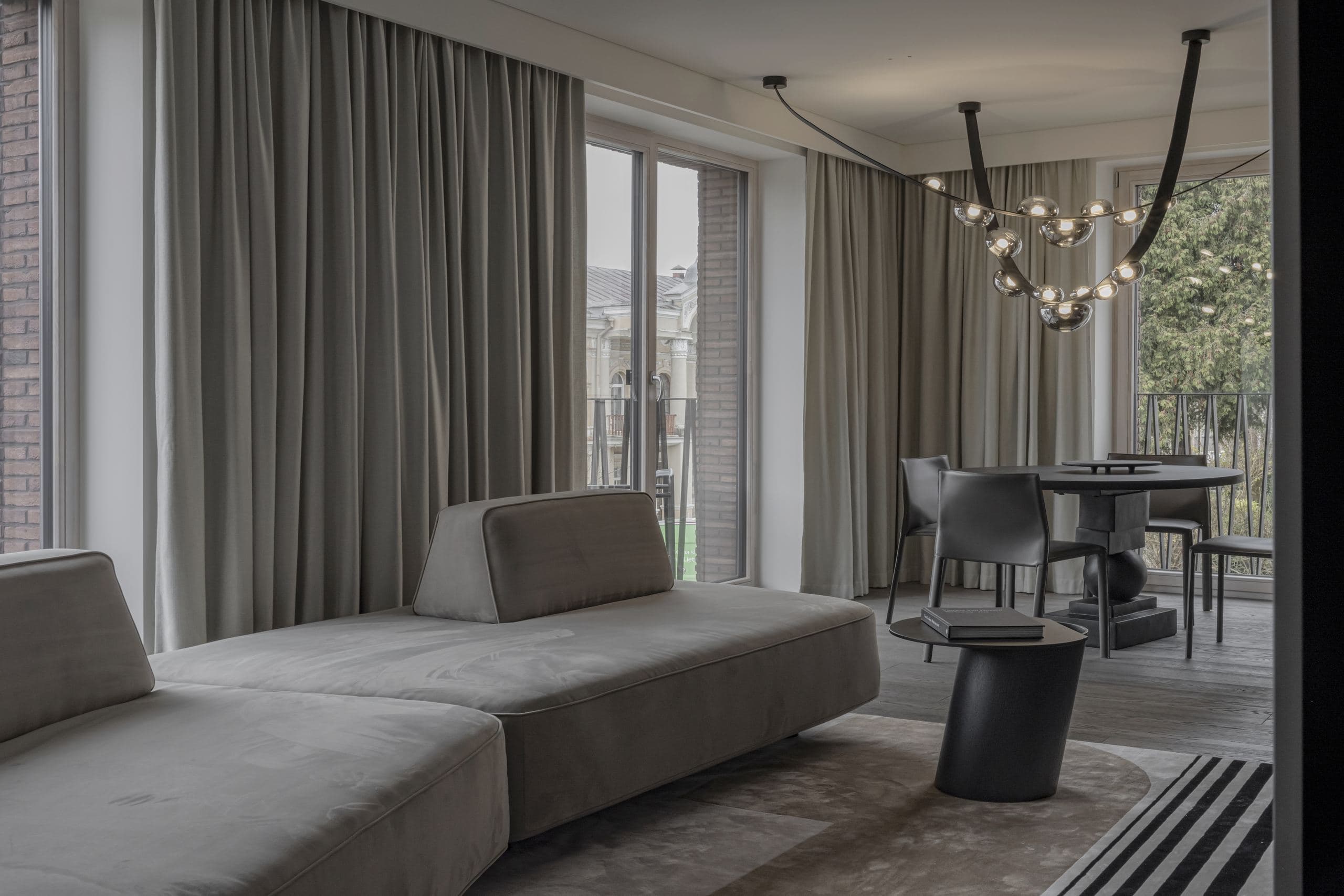 Paupys Apartment — sofa beneath a sculptural branching pendant light by the window