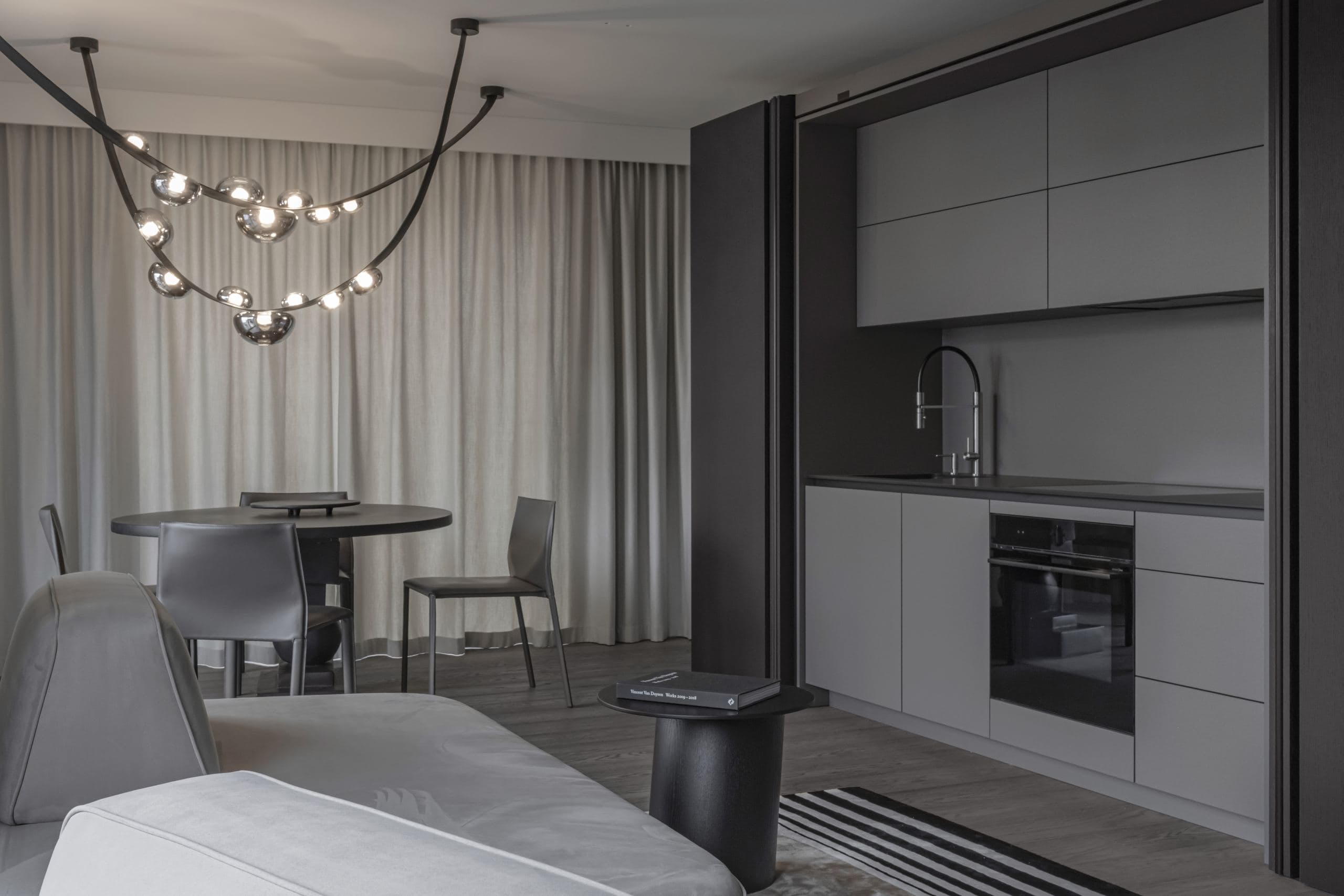 Paupys Apartment — kitchen and dining area beneath a sculptural branching pendant light