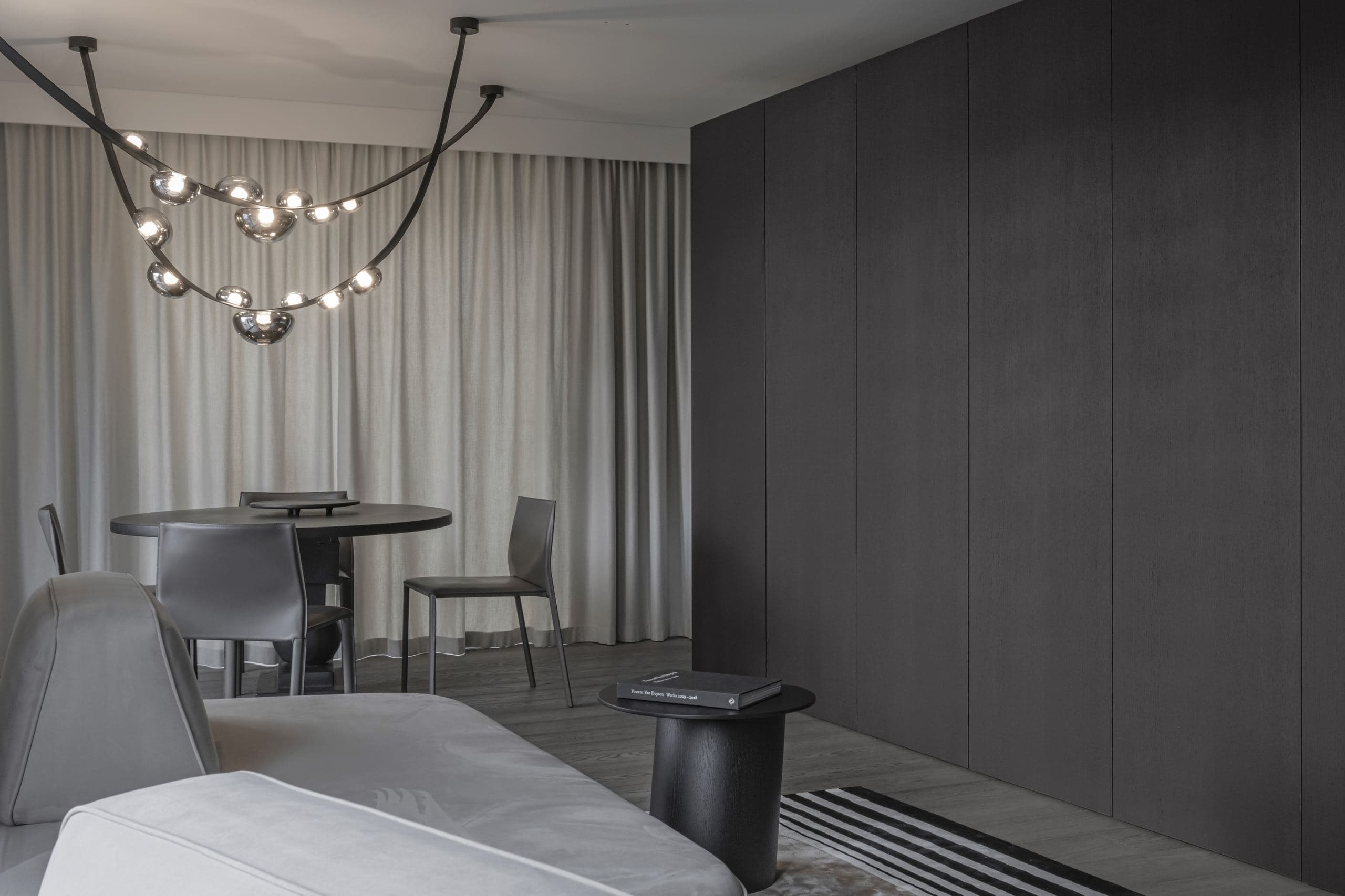 Paupys Apartment — dining table and pendant light beside the bed and a striped rug