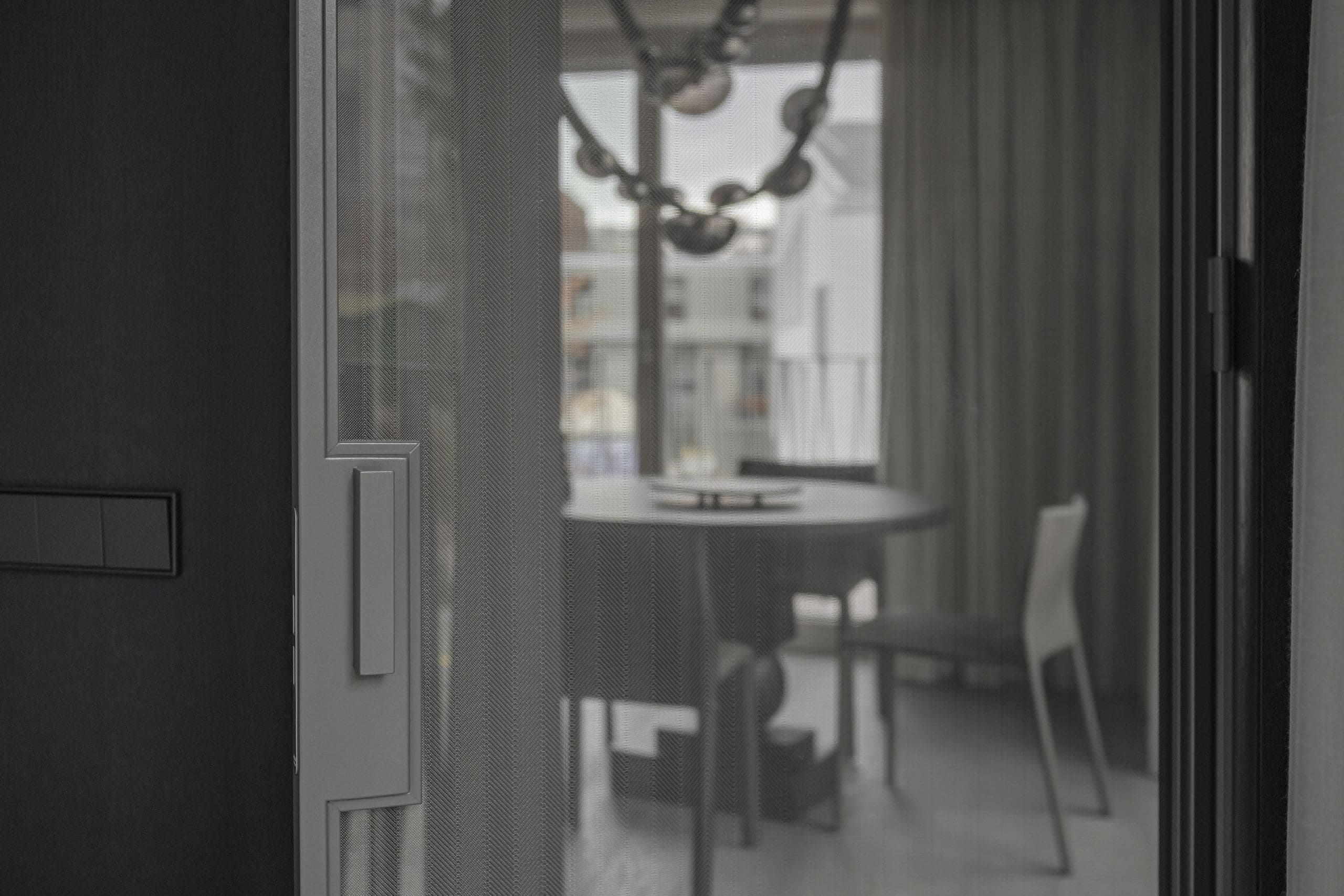 Paupys Apartment — windows framed by the black volume beneath a branching pendant light