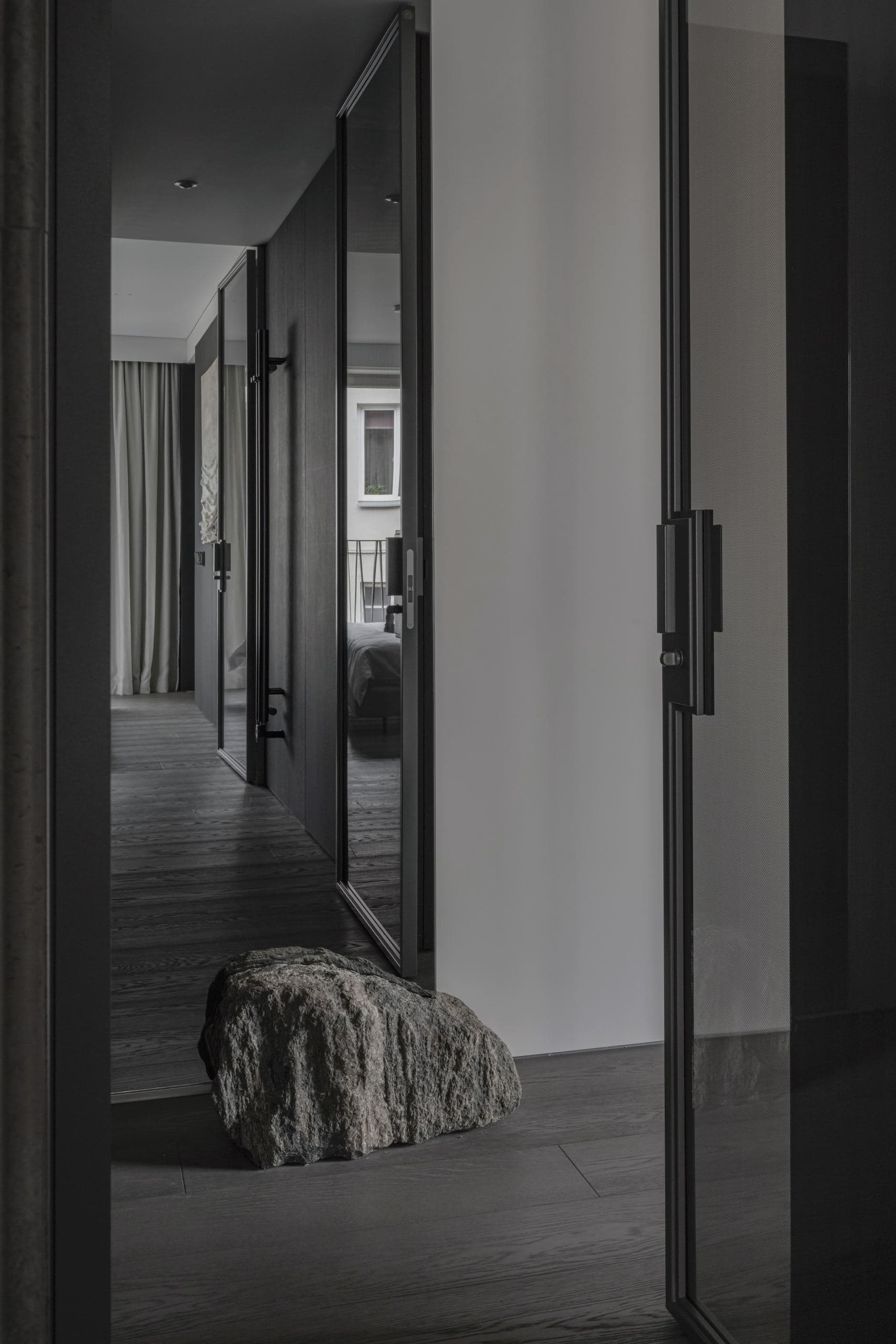 Paupys Apartment — textured stone object beside a mirrored hallway