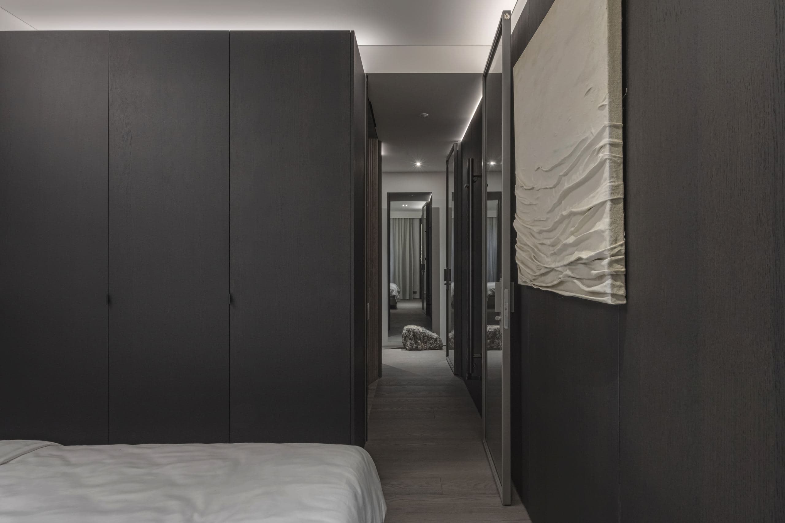 Paupys Apartment — bed beside the black volume and a textured door panel