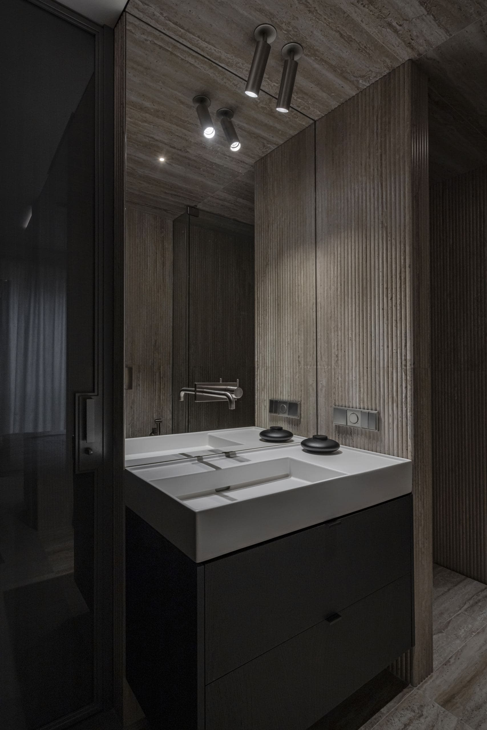 Paupys Apartment — dark stone vanity with round basins beneath a wood ceiling