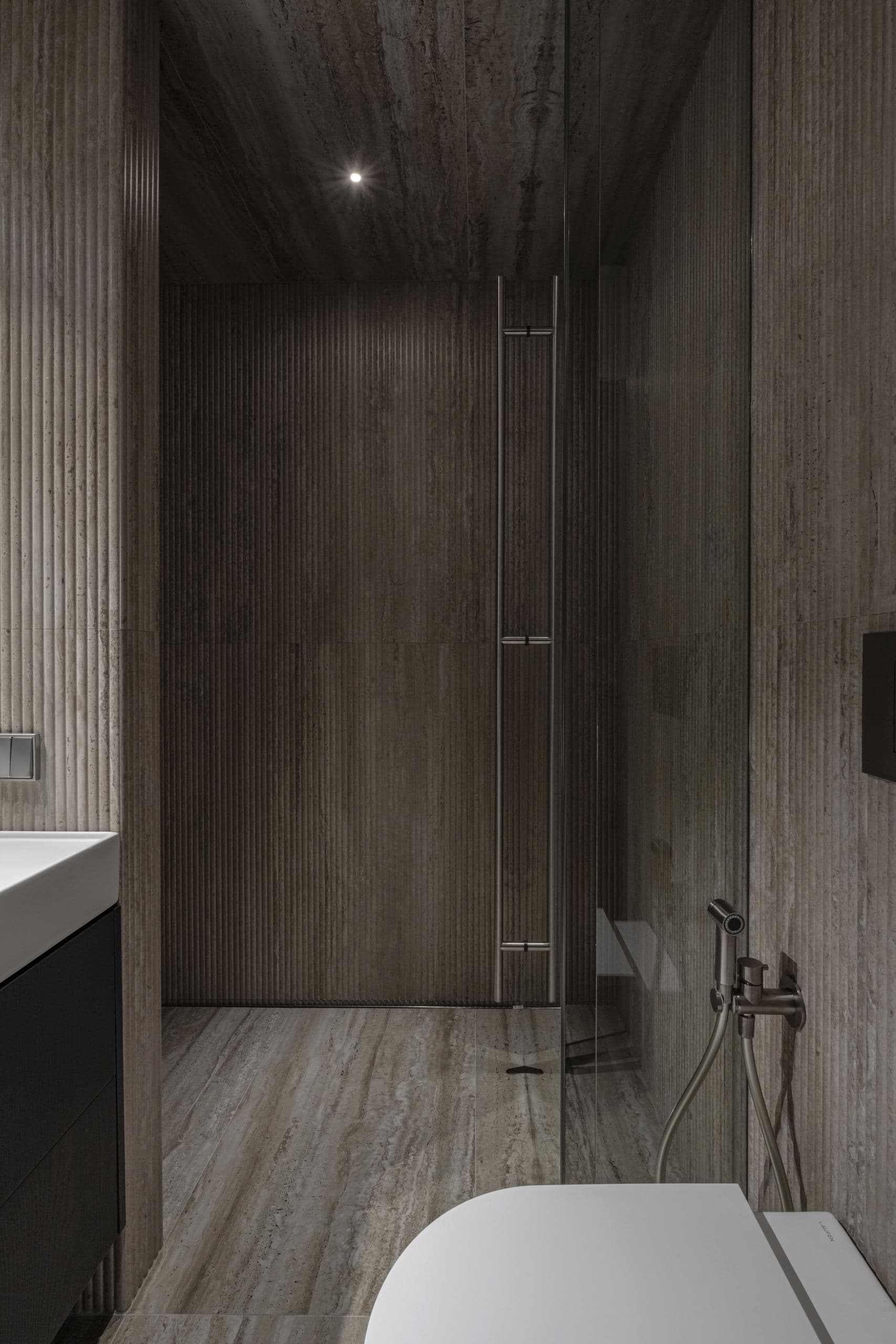 Paupys Apartment — vanity and shower seen through a walnut-panelled doorway