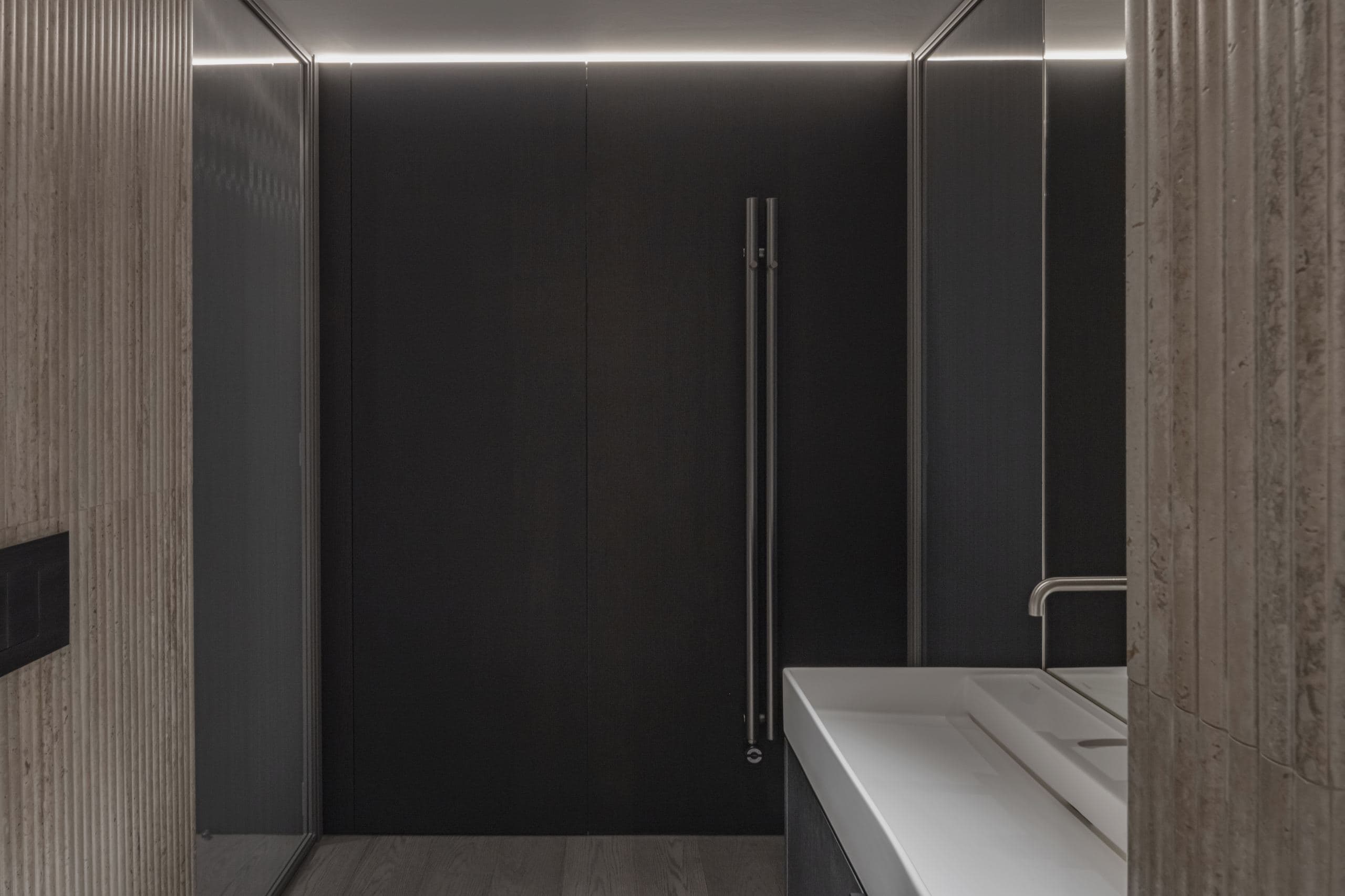 Paupys Apartment — dark stone kitchen counter beside a walnut wardrobe