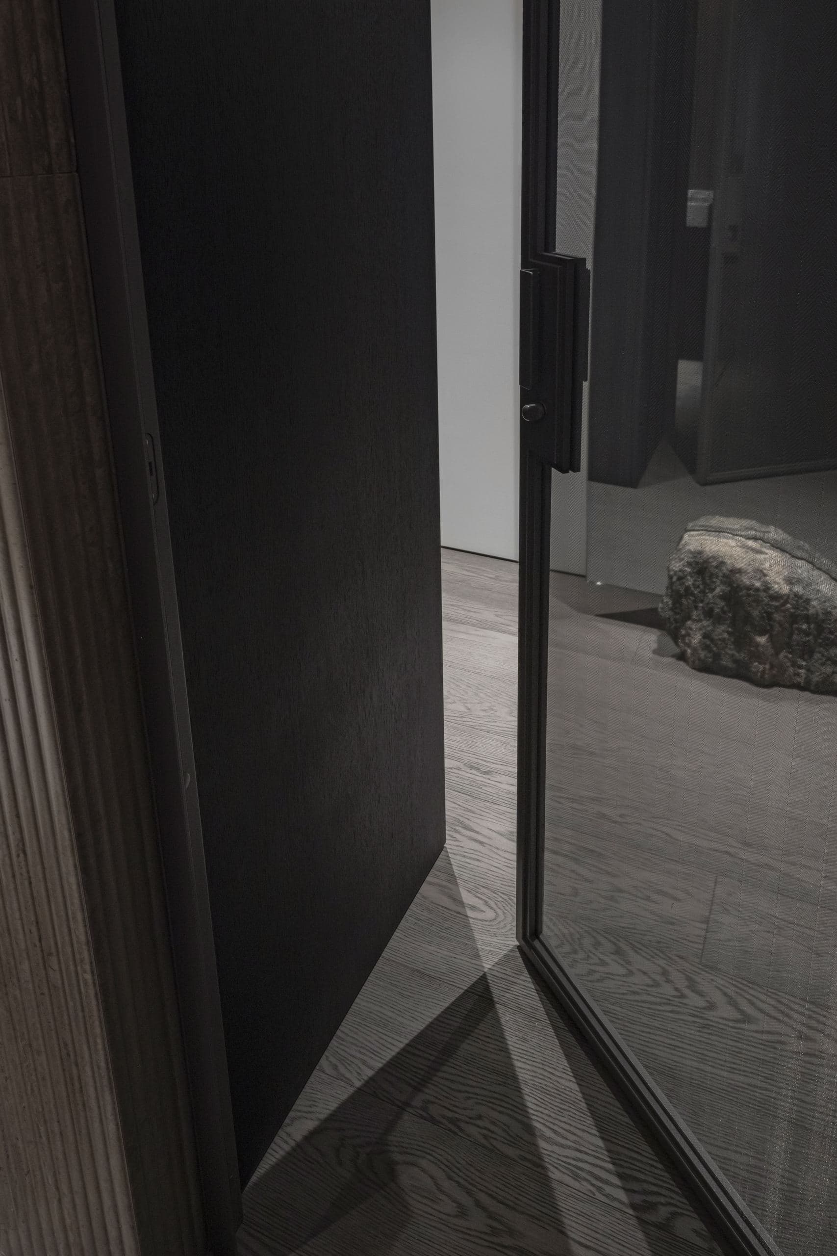Paupys Apartment — door reflecting a textured stone sculpture in a mirrored hallway
