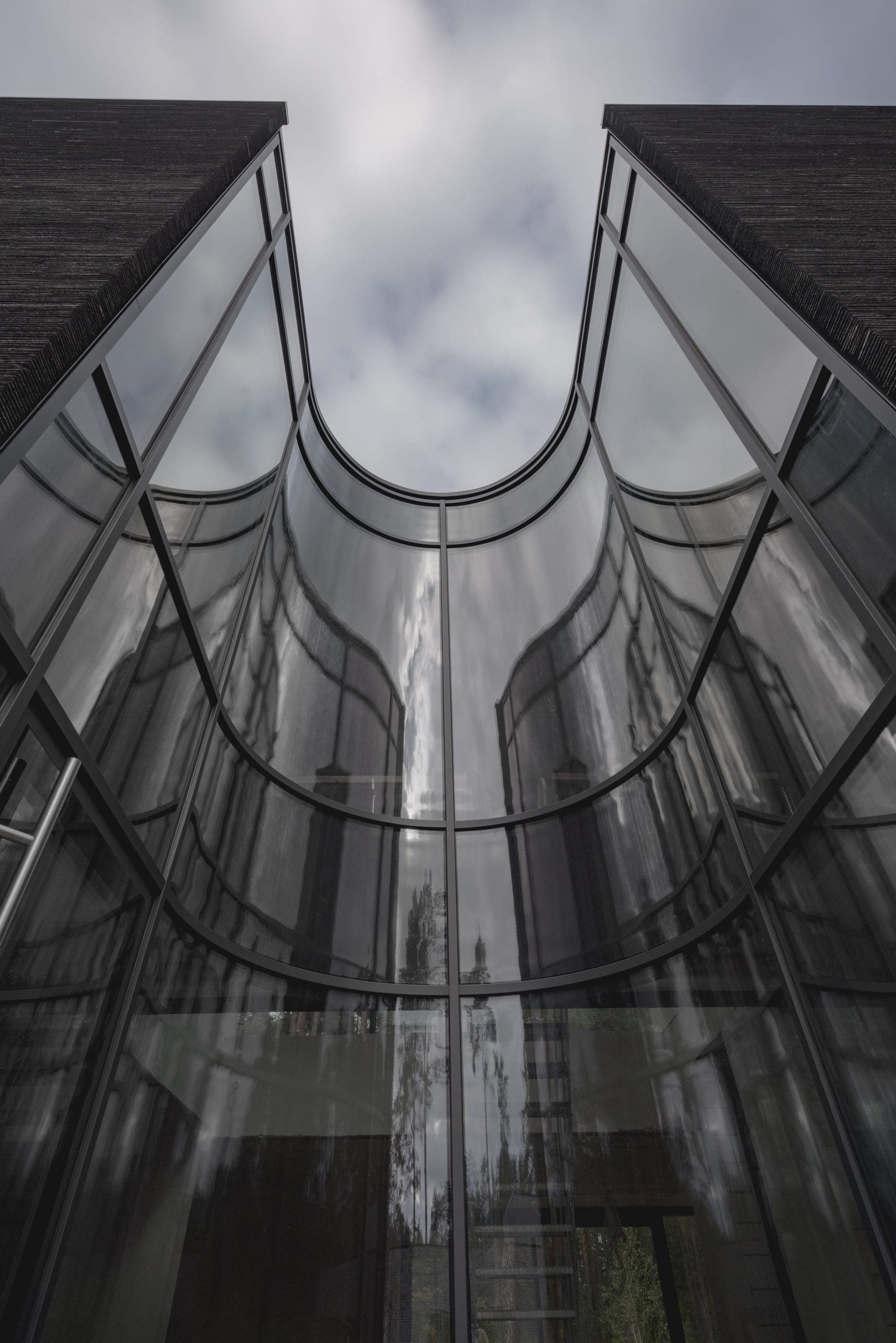 IN JAN House — looking up the curved glass wall between its two stone volumes
