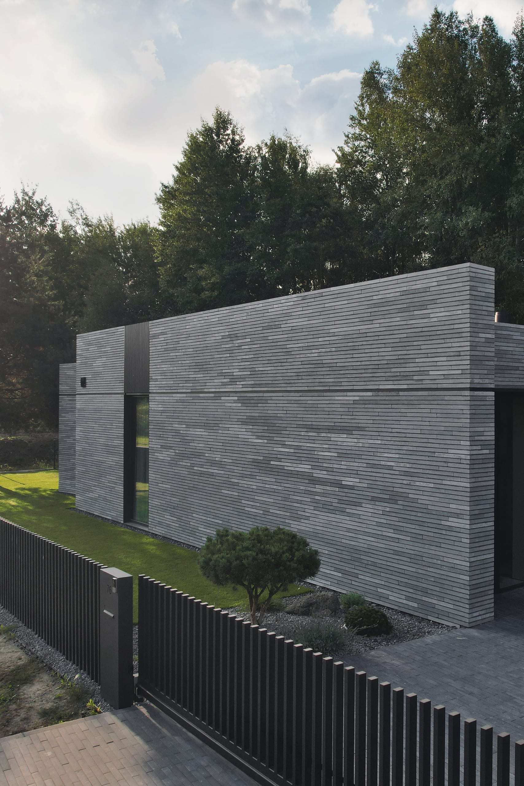 Modern Family House — handmade grey brick coursing above the lawn, over the metal fence