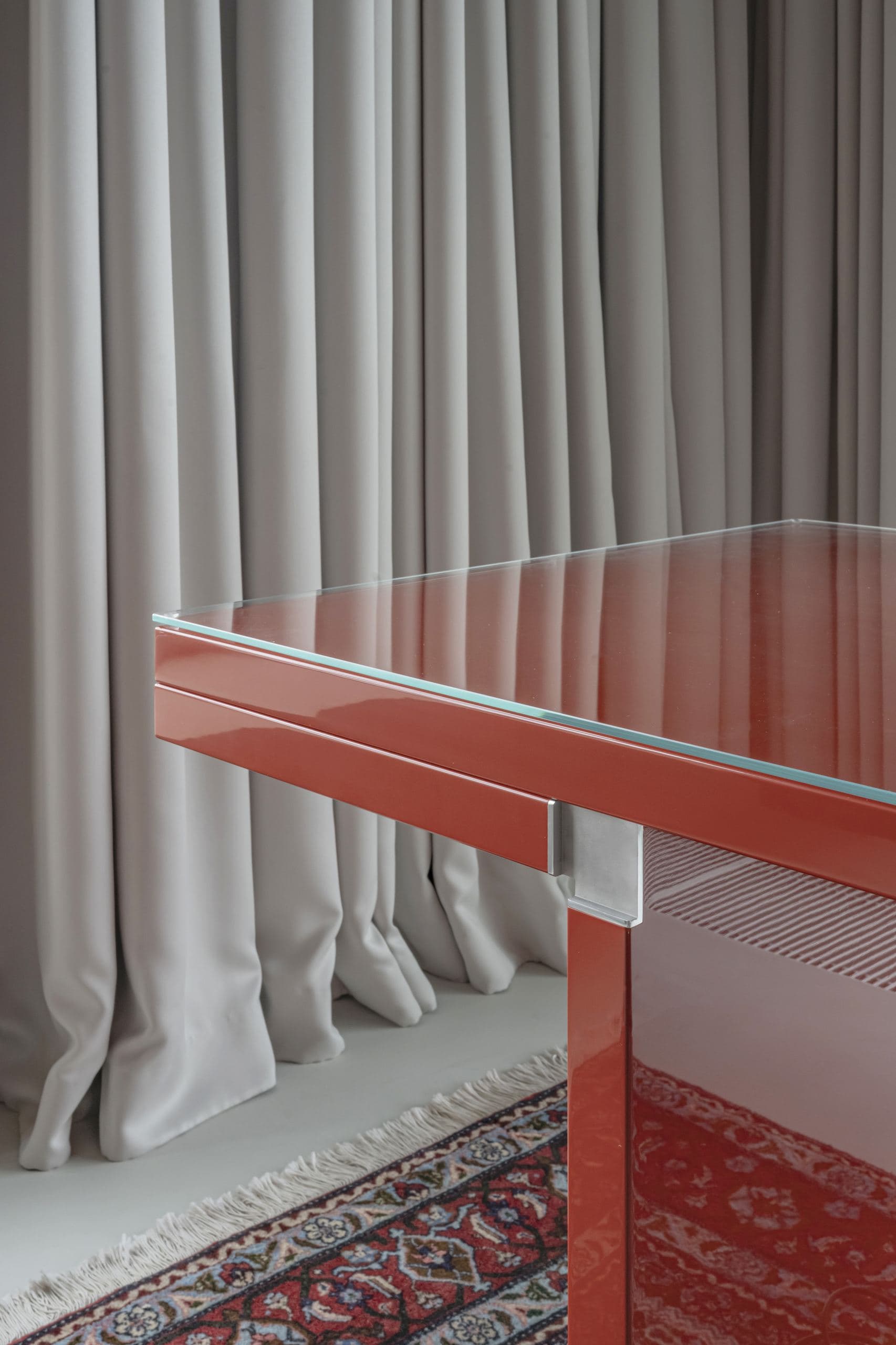 Bespoke Office Interior — detail of a red lacquered desk edge against draped curtains