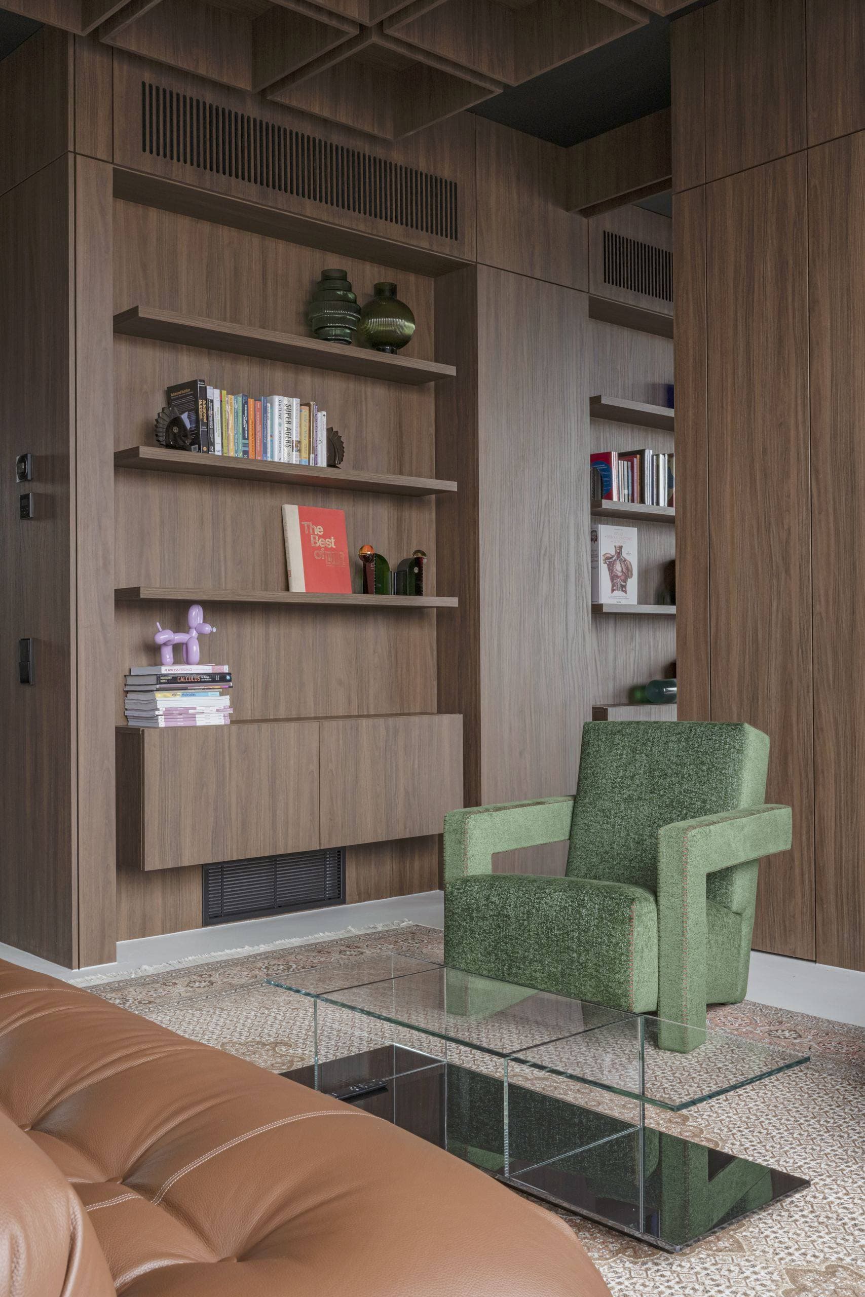 Bespoke Office Interior — green armchair beside walnut shelving filled with books