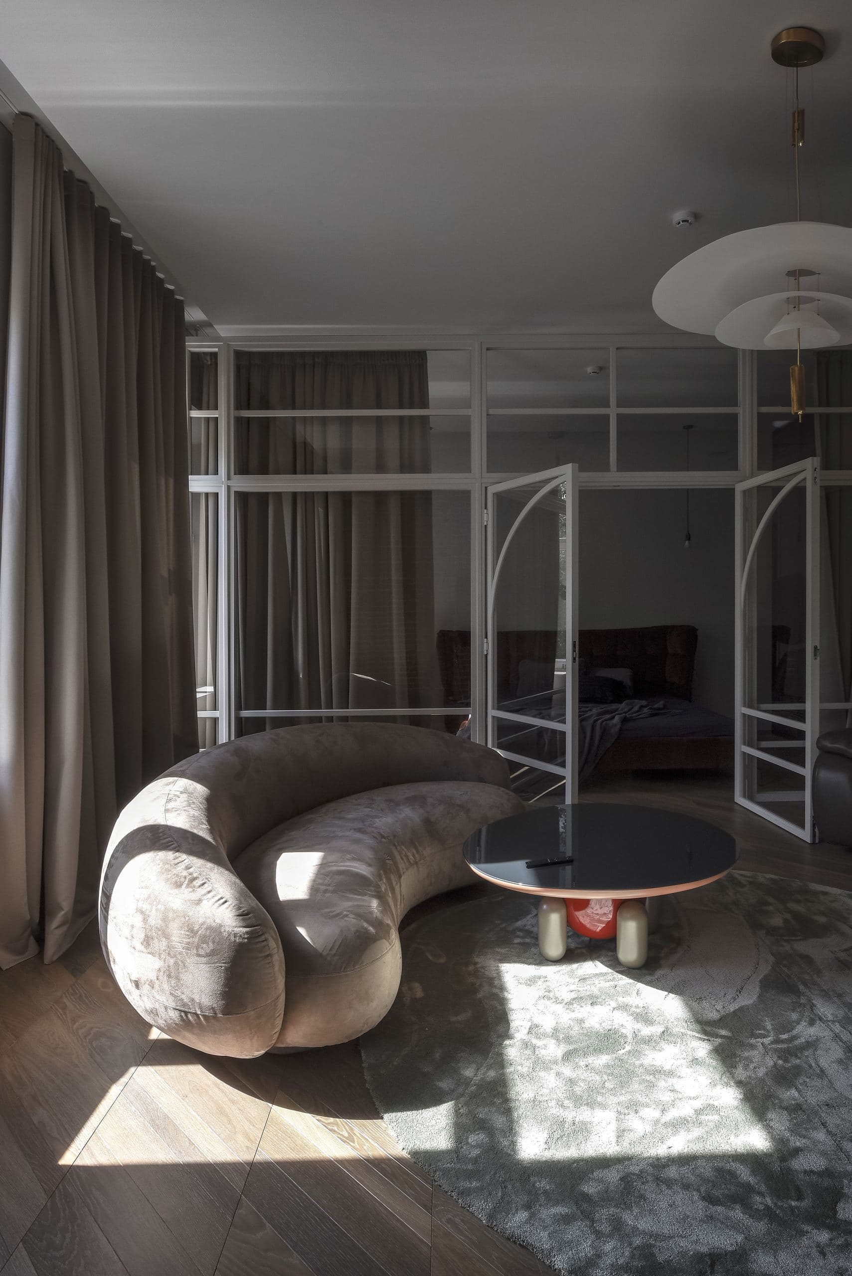 City Avenue Apartment — curved sofa on a patterned rug beneath hanging pendant lights