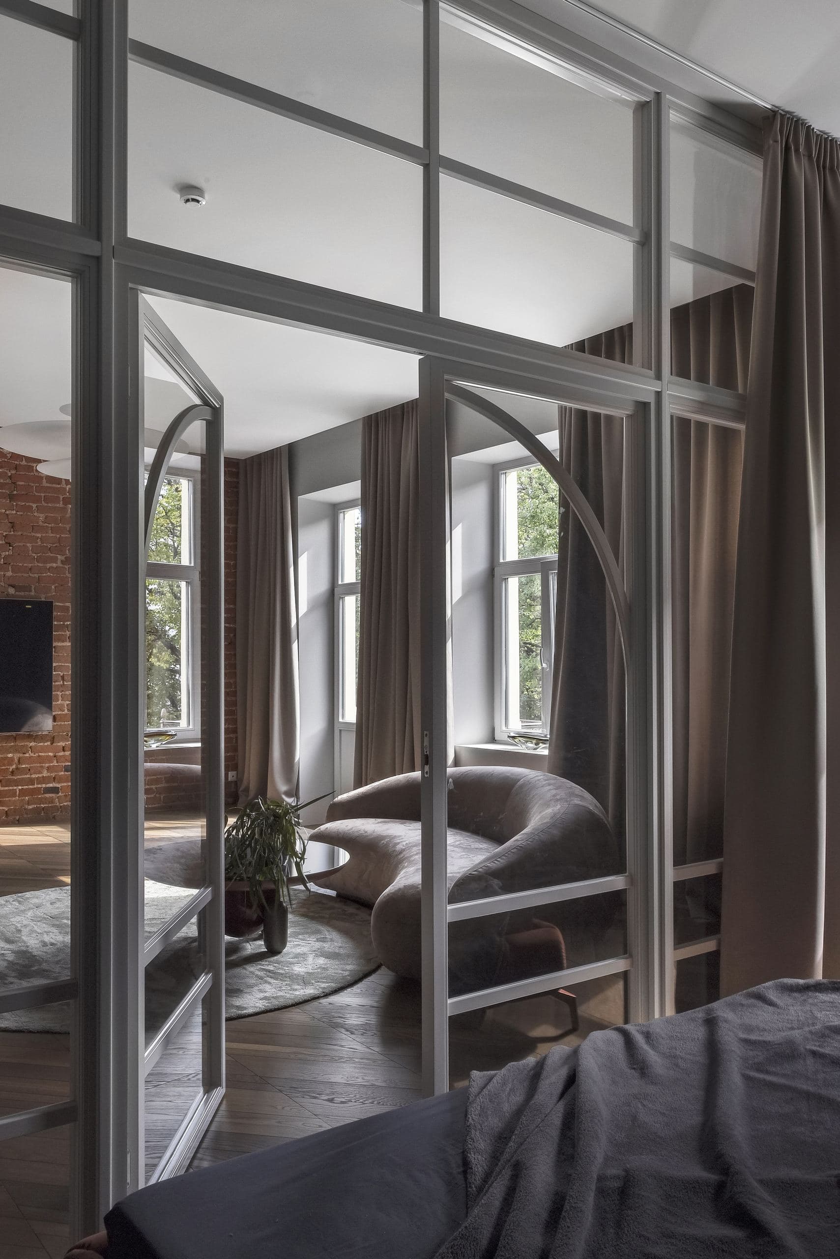 City Avenue Apartment — curved glass partition wall beside a bed