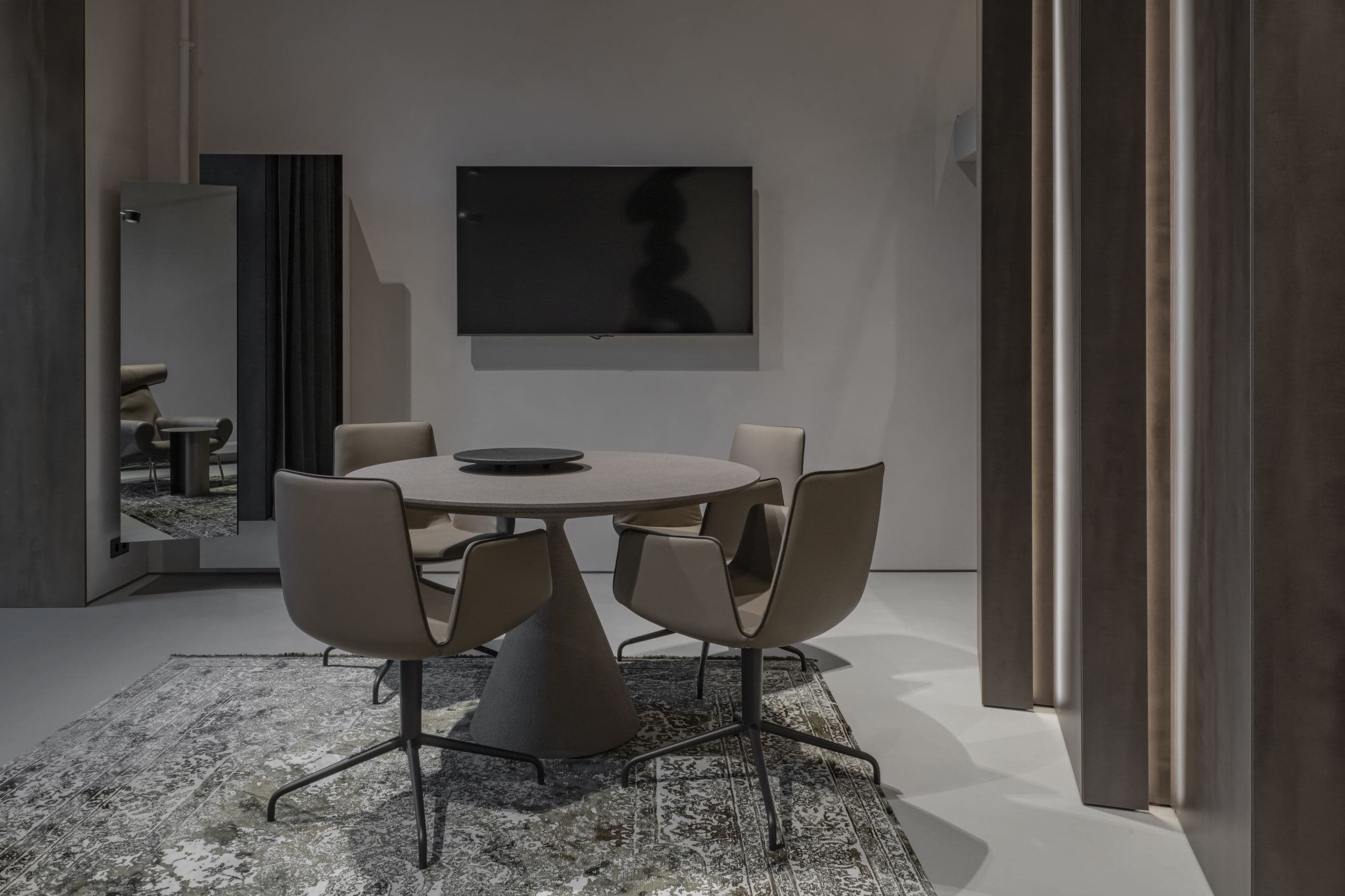 Loft Office — round meeting table reflected in a wall mirror beneath a mounted television