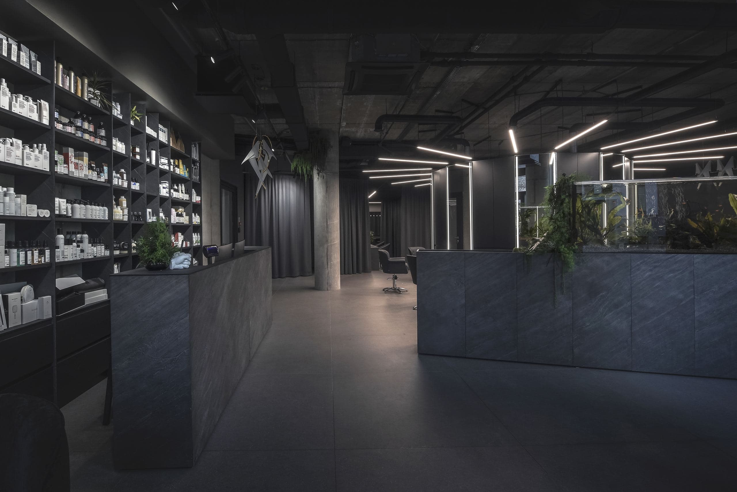 Maestro Beauty Salon — product shelving wall beside the dark stone reception island